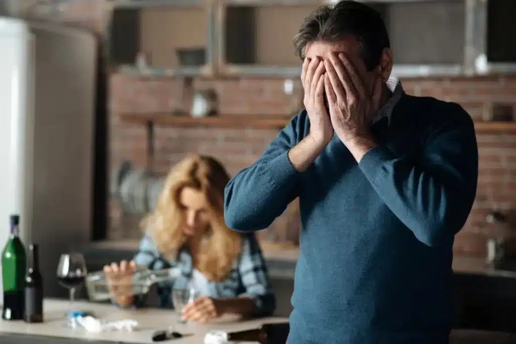 A woman drinking in the backround with an uoset husband