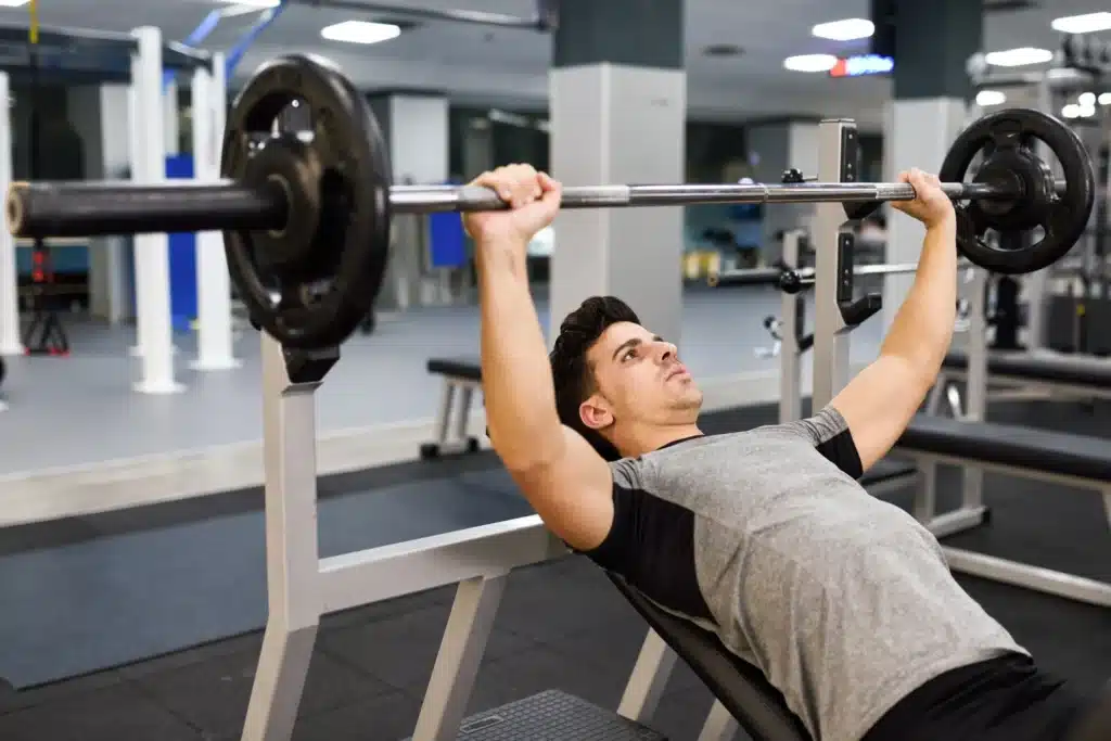 Young man bodybuilder doing weight lifting in gym.