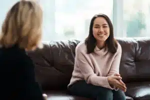 Young woman smiling during a therapy session with a counselor as part of dual diagnosis treatment.